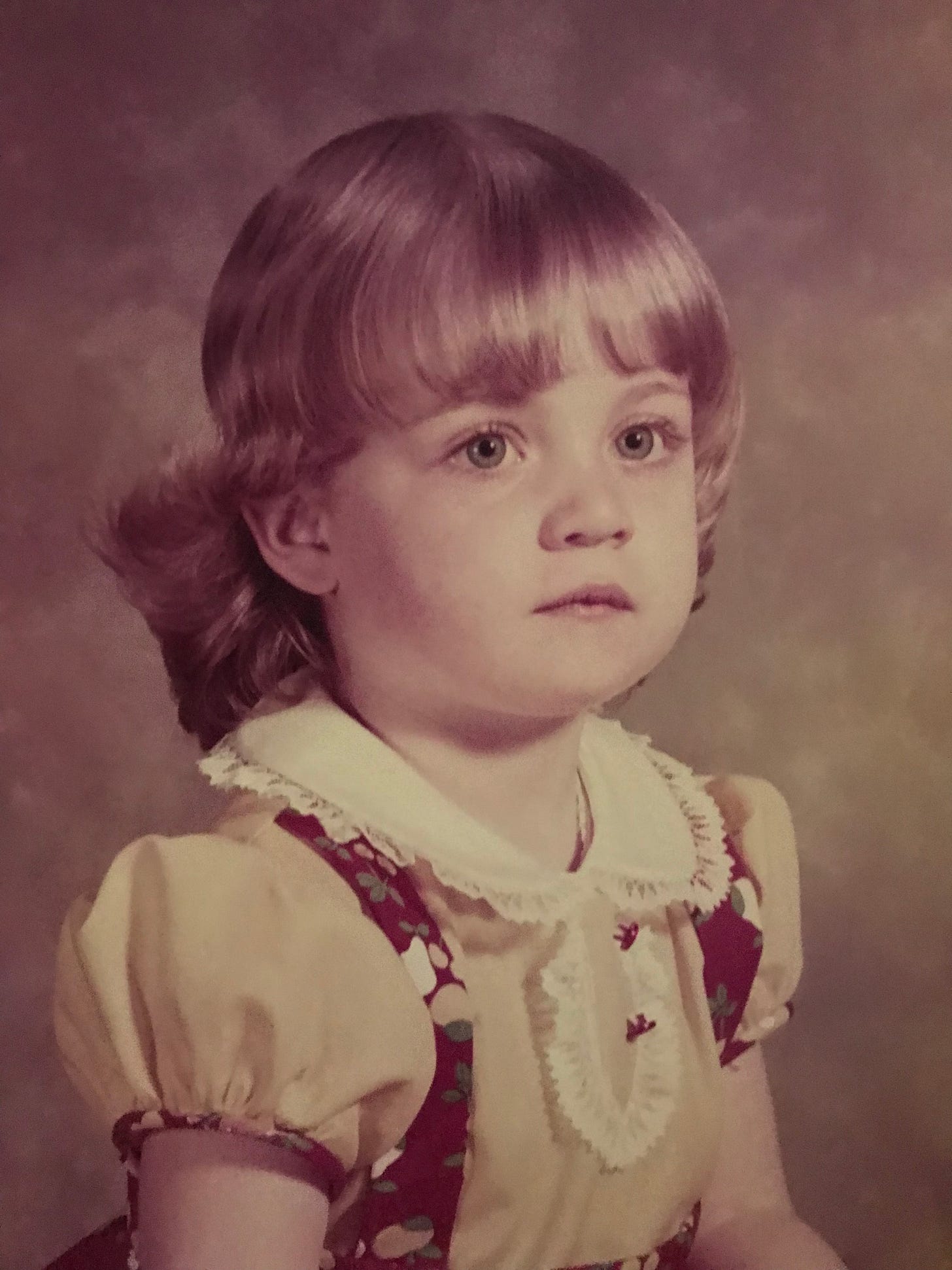 A formal picture of toddler Tracey, unsmiling.
