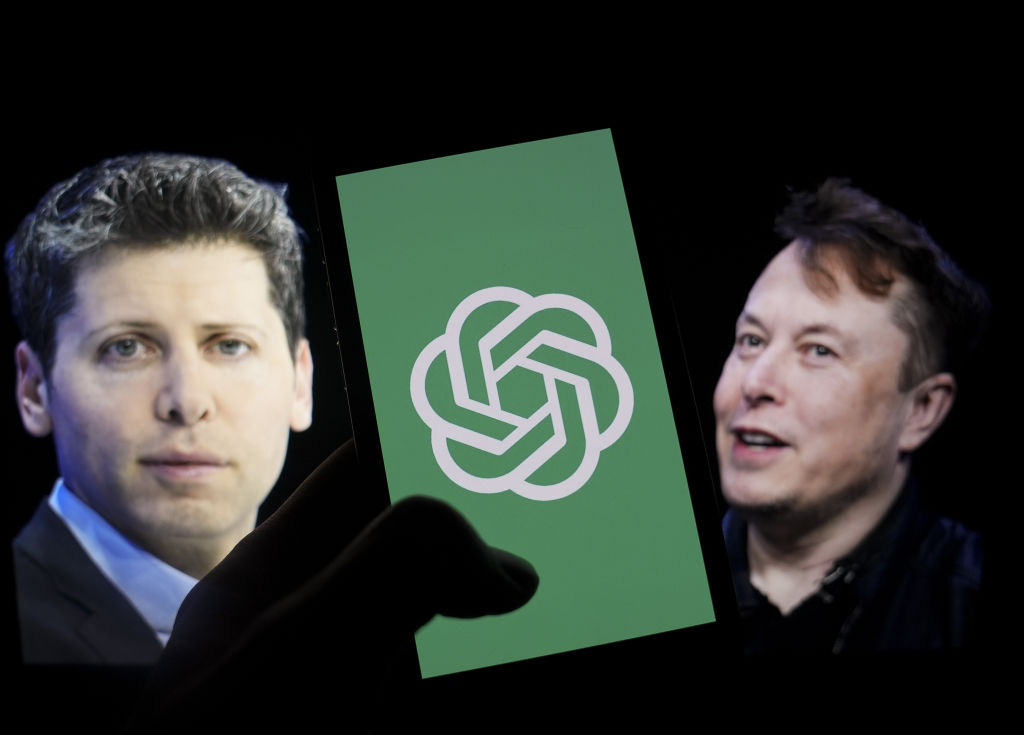 The logo of 'OpenAI' is displayed on a mobile phone screen in front of a computer screen displaying the photographs of Elon Musk and Sam Altman in Ankara, Turkiye on March 14, 2024.