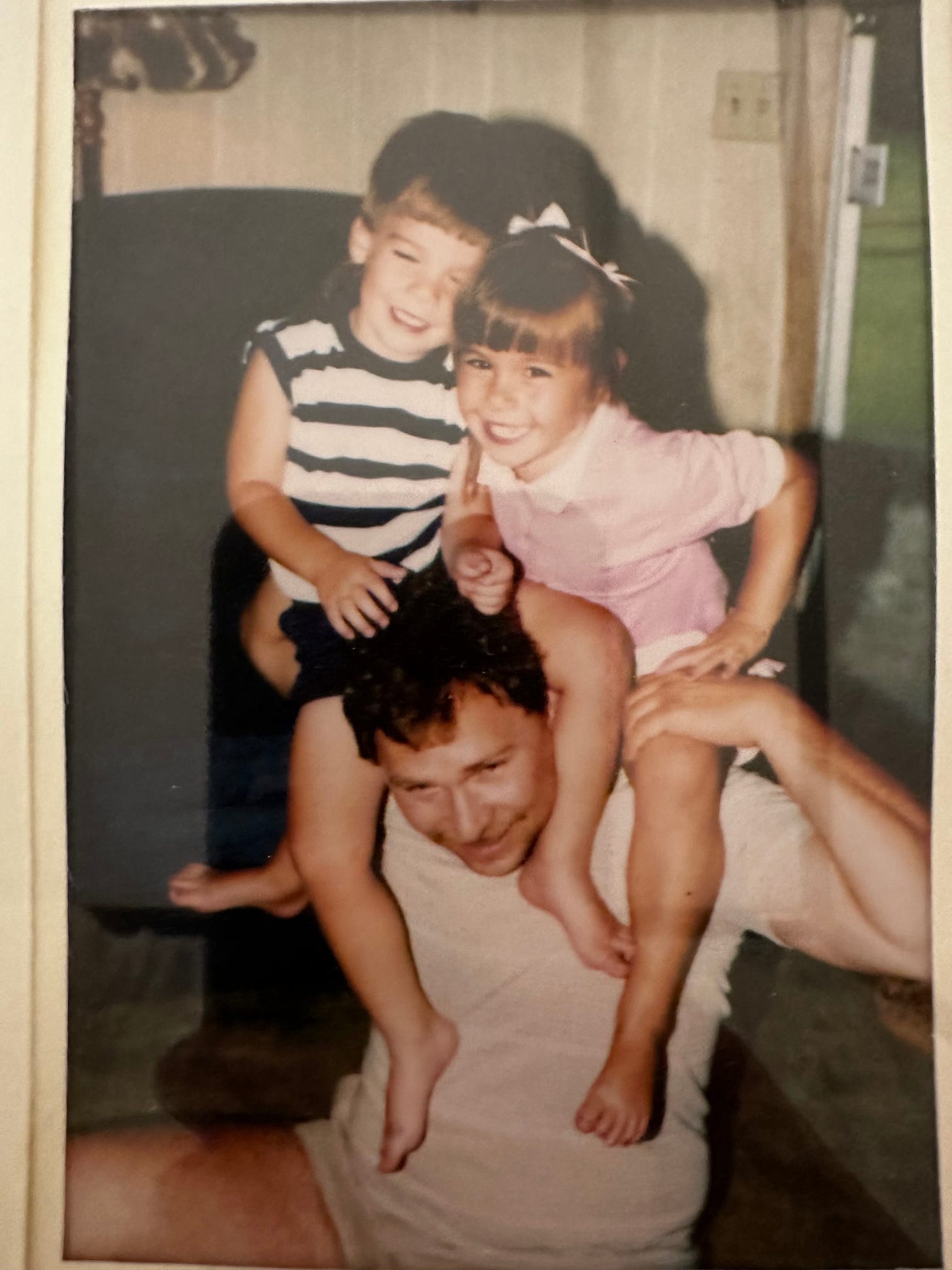 Photo of two young children on father's shoulder