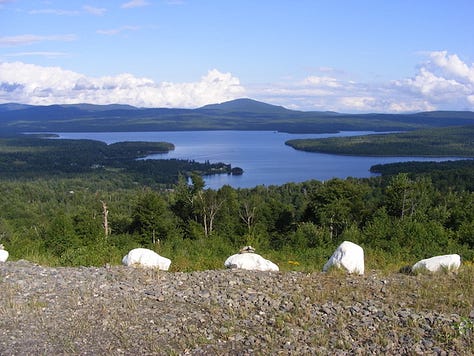 Lake under blue sky, with one mountain in background; icon of Christ and St. Mary; exterior of New Hampshire State House