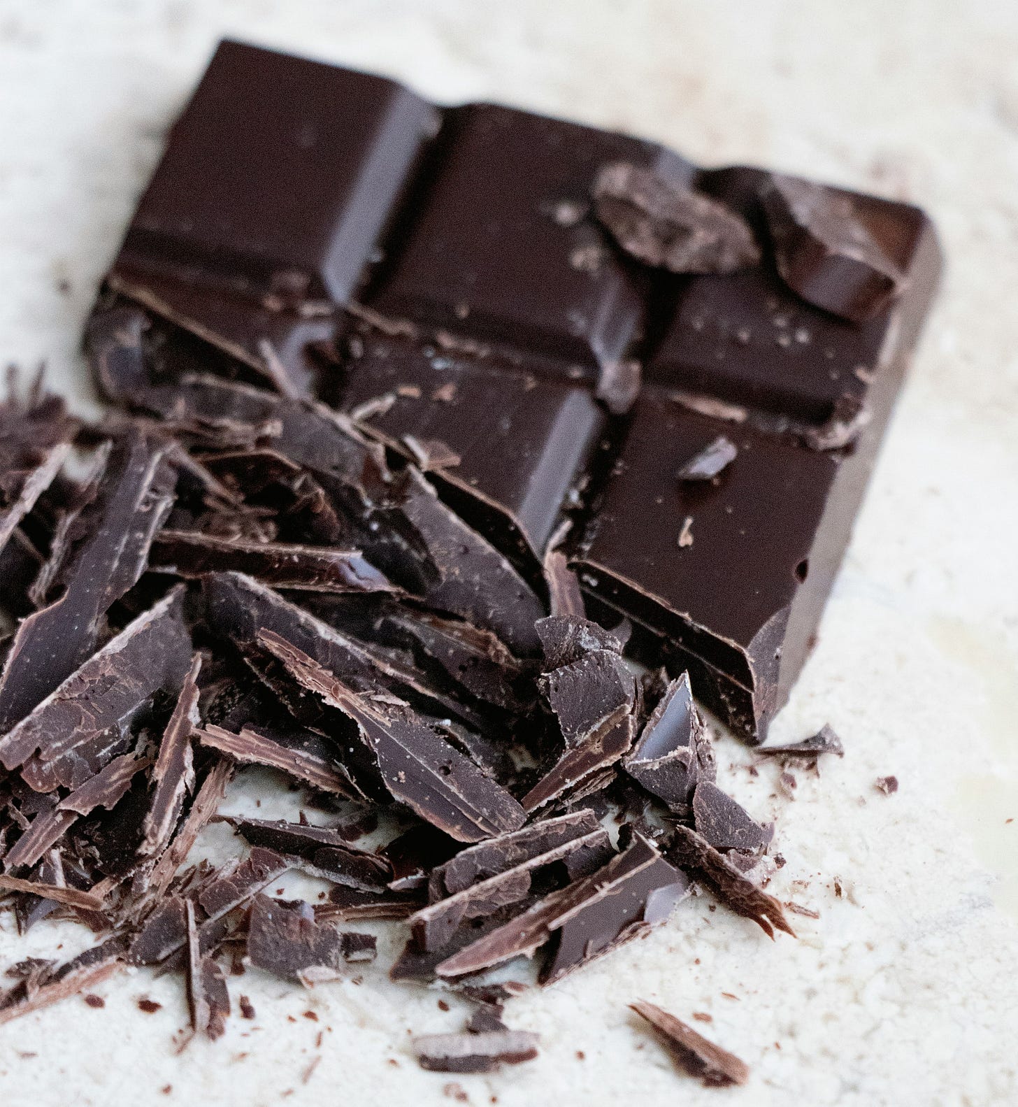 Close-up photo of slivered dark chocolate on a white table. 