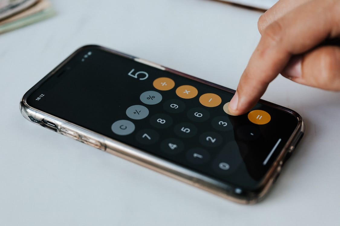 Free Crop anonymous economist using calculator app on smartphone at work Stock Photo