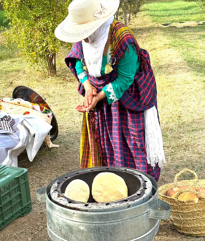 Four photographs: A woman in a colorful dress stands above a cylindrical oven with rounds of bread clutching the sides; a photograph of cooking urns beside small pits used for cooking; a photograph of a tree with large woven mats beneath it, set with plates; a green serving dish filled with a hearty stew with chickpeas and olives.