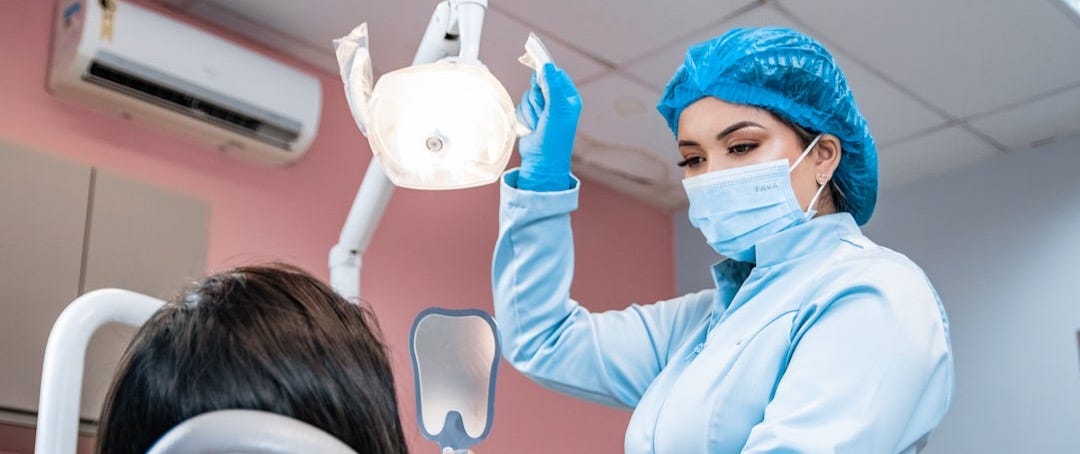 a woman getting her teeth checked by a dentist a woman getting her teeth checked by a dentist