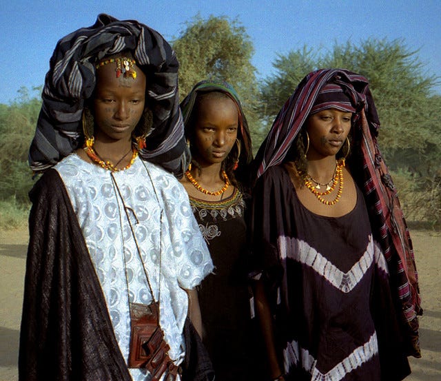 Lovette Jallow wearing yellow during a cultural gathering—scarification visible as a marker of Fulani ancestral lineage and belonging.