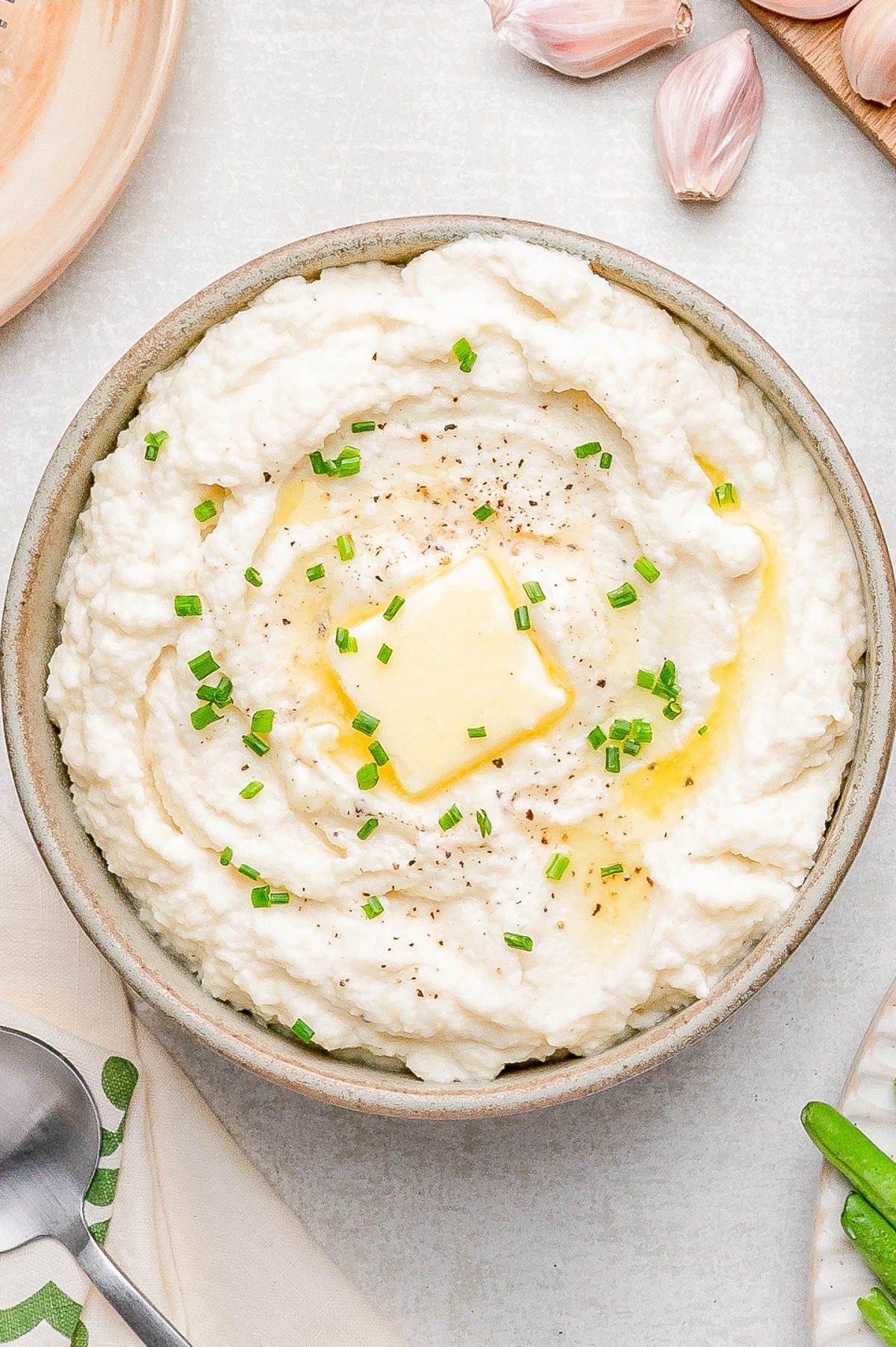 A bowl of mashed potatoes topped with a pat of melting butter, chopped chives, and cracked black pepper. A bowl of mashed potatoes topped with a pat of melting butter, chopped chives, and cracked black pepper.