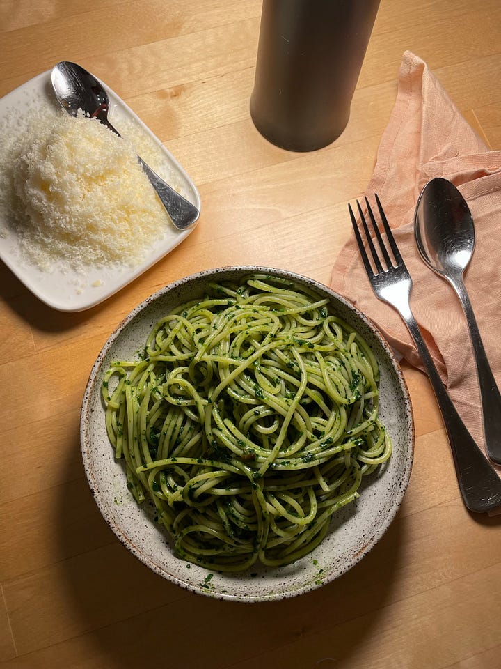 A big bowl of green garlic butter spaghetti, a pile of finely grated parmesan cheese nearby. A bowl of soba noodles topped with grilled salmon and beans.