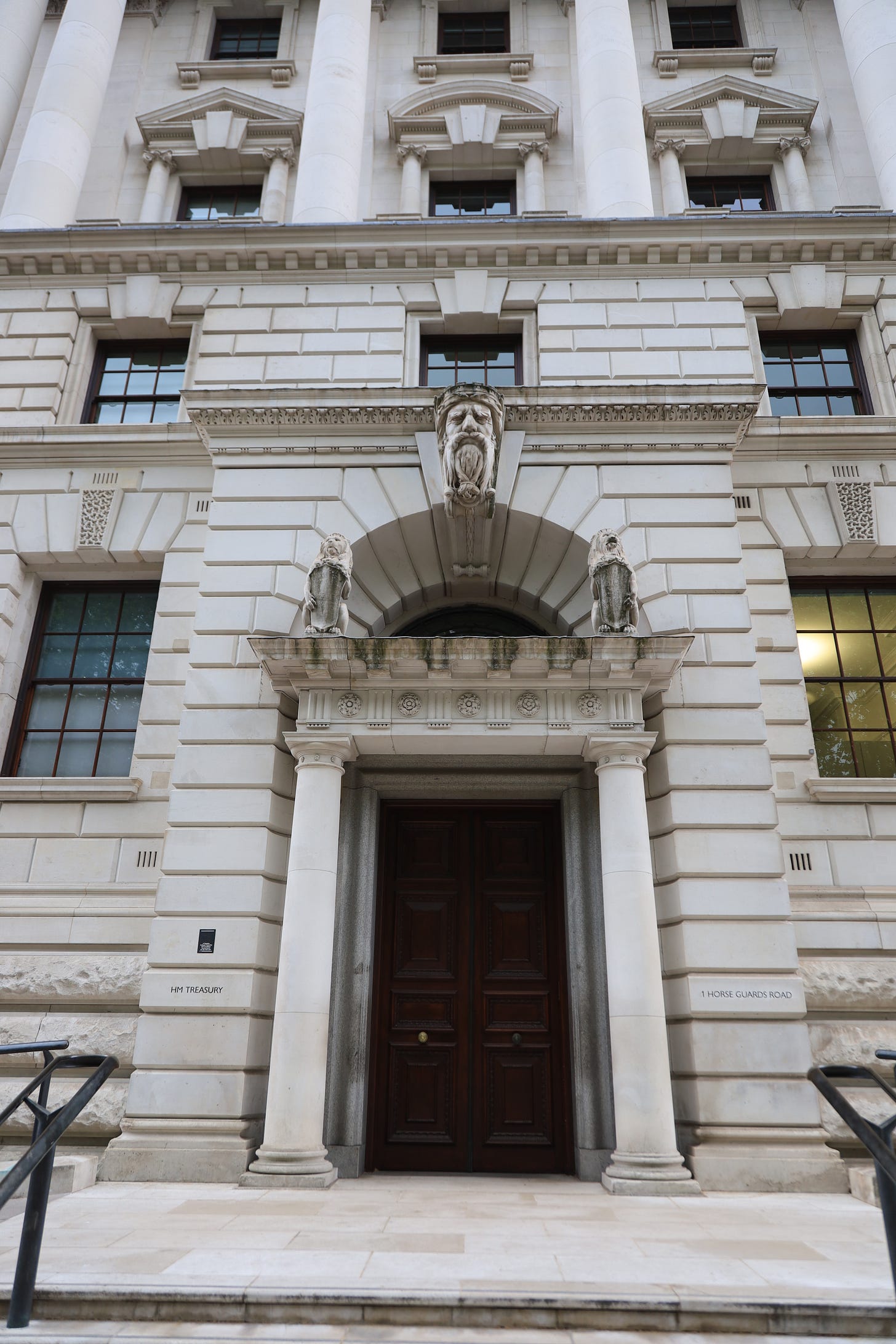 Classical white stone government building entrance with ornate carved details and columns Classical white stone government building entrance with ornate carved details and columns