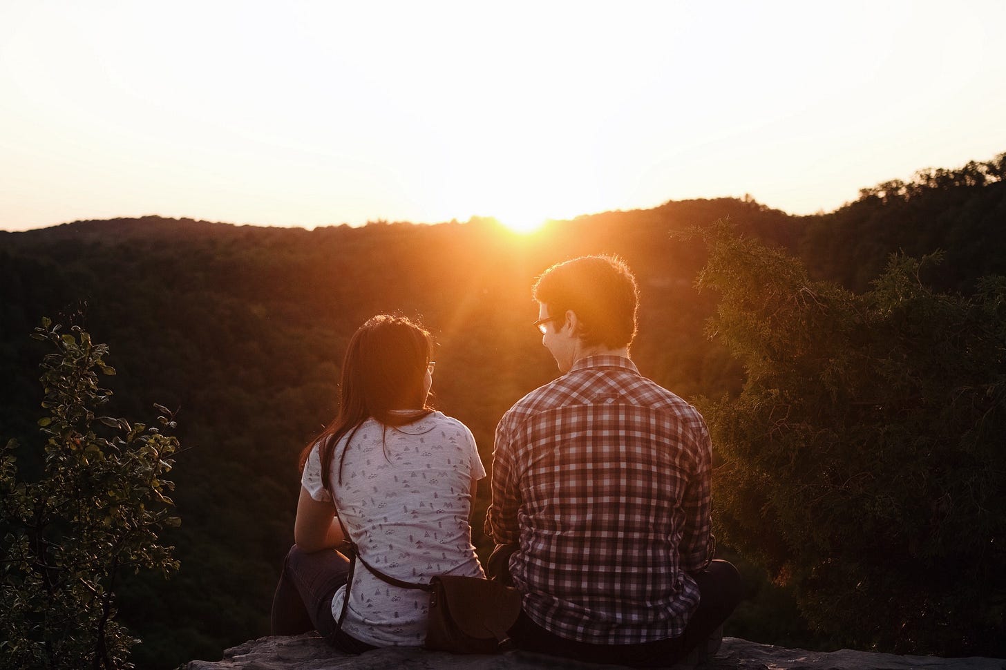 A couple chat on a hill top as the sun sets over the horizon. A couple chat on a hill top as the sun sets over the horizon.