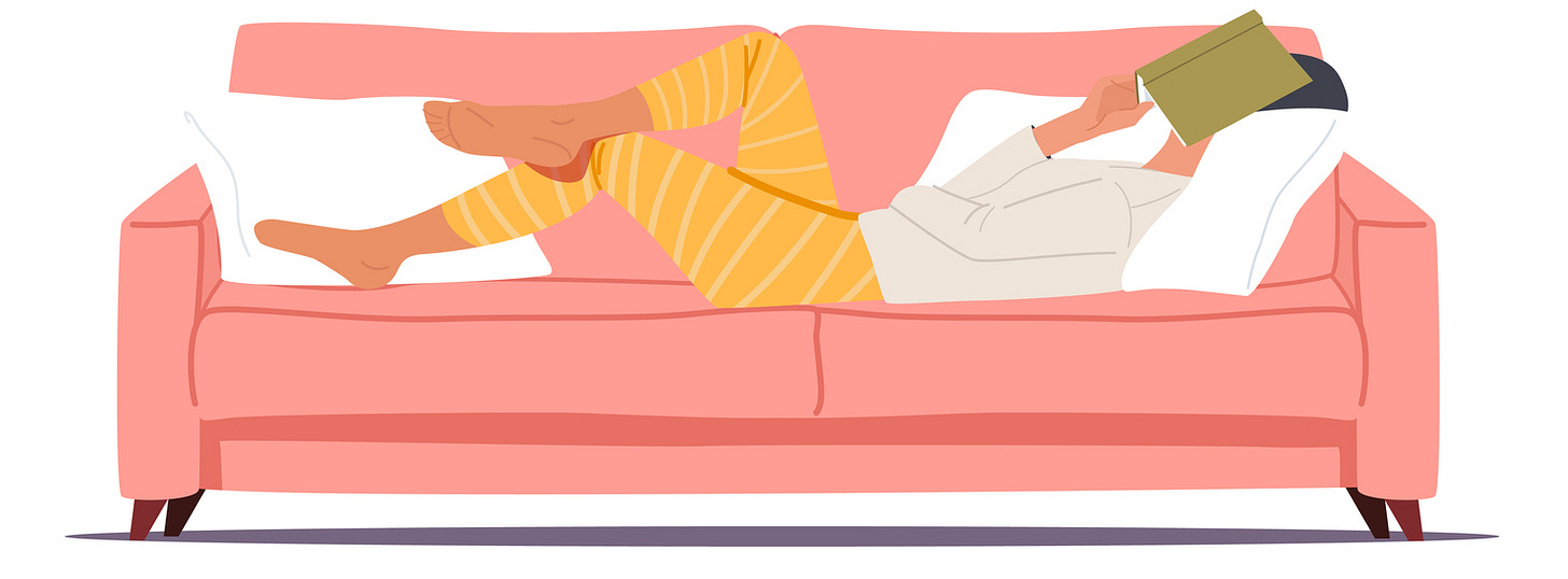 Woman lying on couch, covering her face with a book.