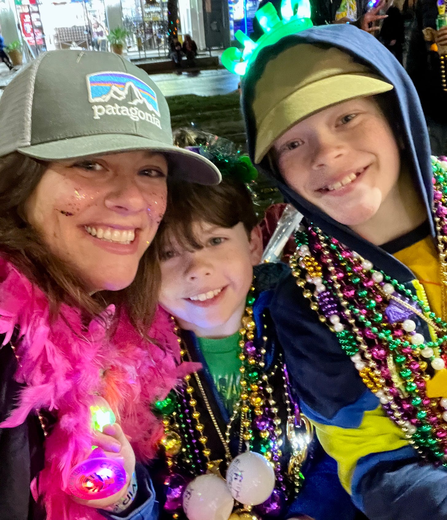 Brett and her two boys celebrating Mardi Gras with layers of colorful necklaces