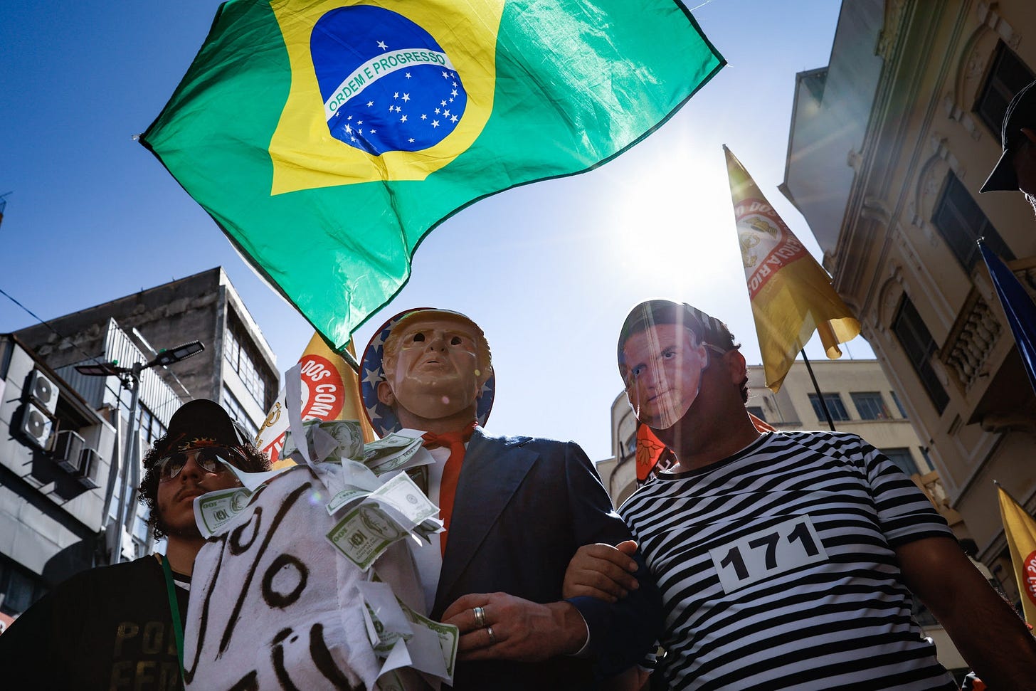 Demonstrators wear masks in the likeness of US President Donald Trump and Jair Bolsonaro, Brazil&#39;s former president, during a Retail Workers Union protest on 25 de Marco Street in Sao Paulo, Brazil, on Friday, July 18, 2025. US President Donald Trump ratcheted up pressure on Brazil to drop criminal charges against former President Jair Bolsonaro, saying he would be “watching closely” for a response just a week after threatening to impose punishing tariffs on the South American nation. Photographer: Tuane Fernandes&#x2F;Bloomberg