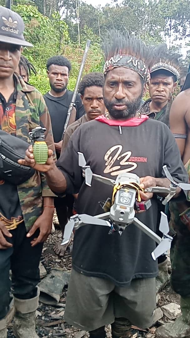 Lamek Taplo holding a downed DJI Mavic drone and Pindad grenade