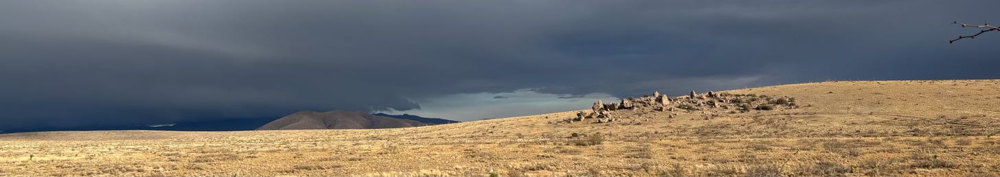 desert landscape with rock formation, mountain and stormy sky