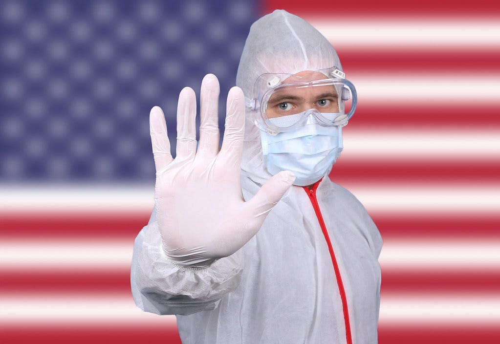 Doctor or Nurse Wearing Medical Personal Protective Equipment (PPE) Against The Flag Of USA Doctor or Nurse Wearing Medical Personal Protective Equipment (PPE) Against The Flag Of USA