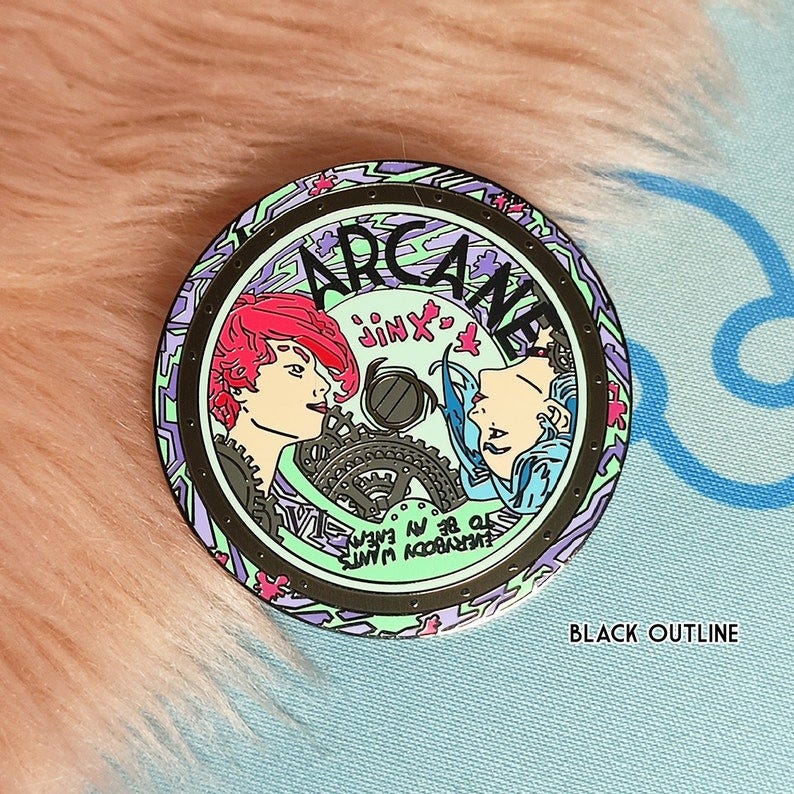 May include: A round, metal pin with a green, purple, and black design. The pin features two characters from the show Arcane, one with pink hair and the other with blue hair. The pin has the word 'ARCANE' written in a circular pattern around the characters. The words 'Jinx' and 'Everybody wants to be my enemy' are also written on the pin. May include: A round, metal pin with a green, purple, and black design. The pin features two characters from the show Arcane, one with pink hair and the other with blue hair. The pin has the word 'ARCANE' written in a circular pattern around the characters. The words 'Jinx' and 'Everybody wants to be my enemy' are also written on the pin.