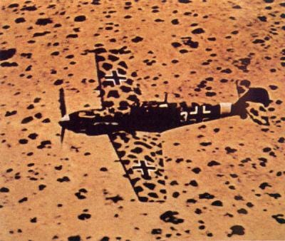 A German Messerschmidt Bf-109 light fighter, featuring distinctive 'desert' camouflage, soaring over Libya in 1942.