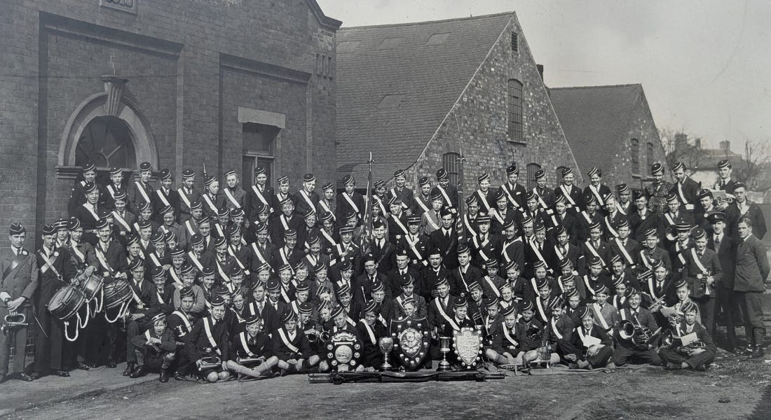 A black and white photo of a large group of brigade members posing in uniform A black and white photo of a large group of brigade members posing in uniform