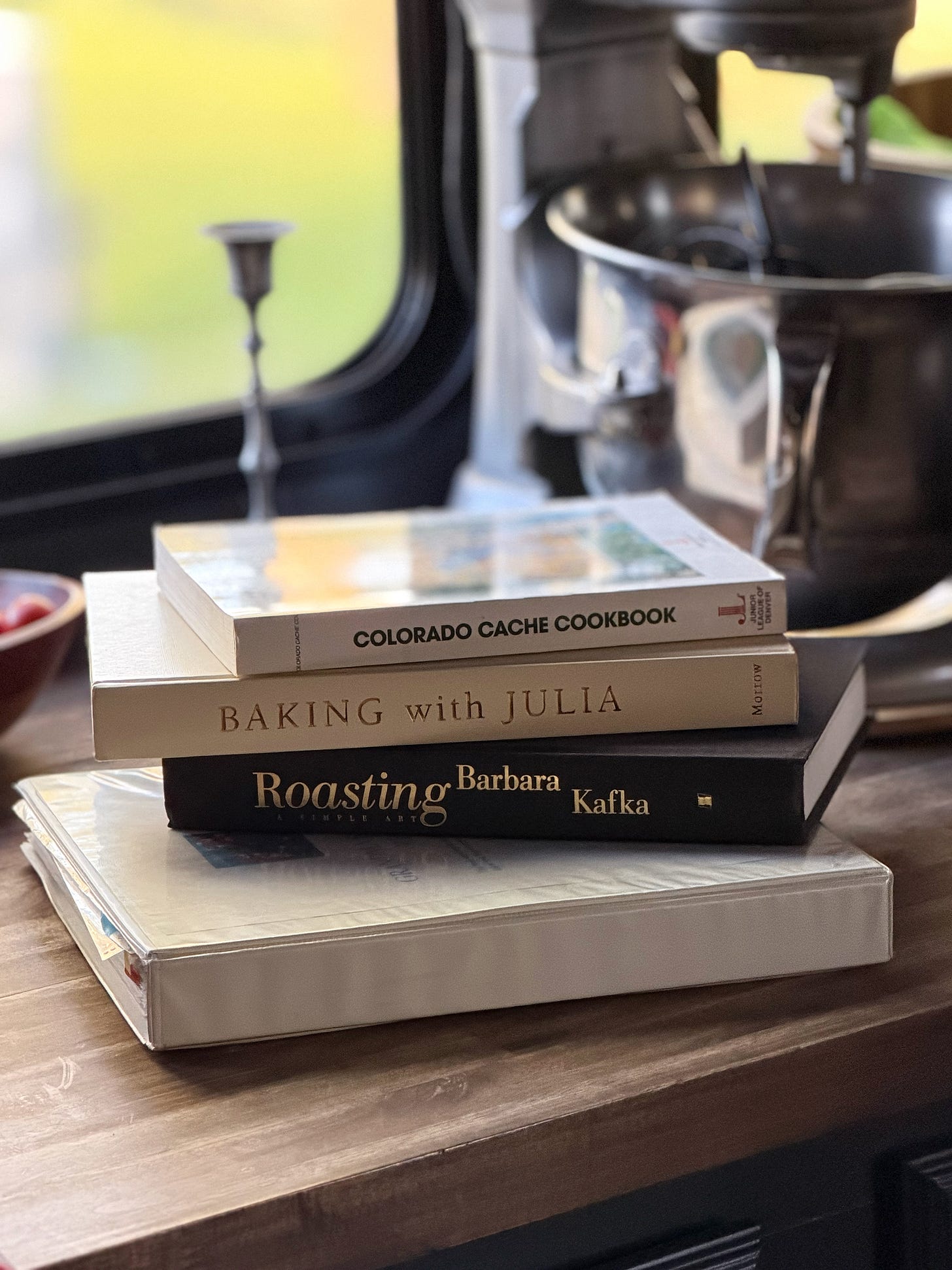 A stack of four cookbooks on a kitchen counter. A stack of four cookbooks on a kitchen counter.