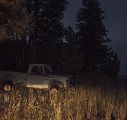 This may contain: an old pick up truck parked in the middle of a grassy field at night time