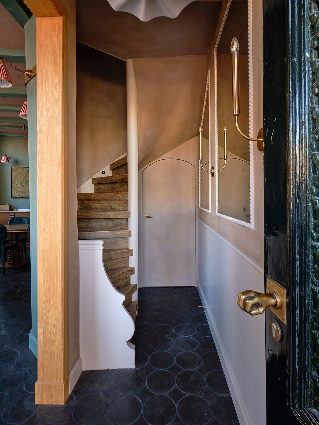 Curving wood staircase in pink hallway