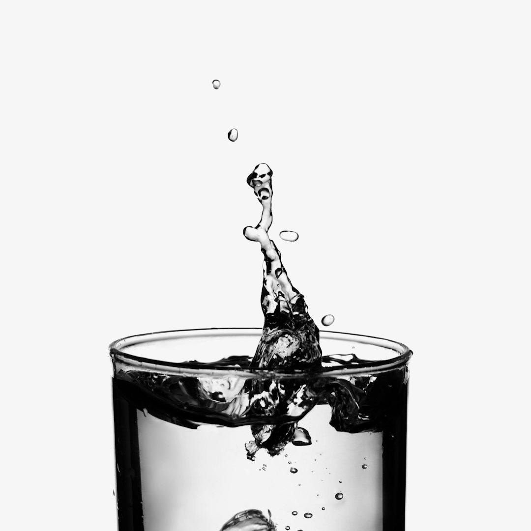 A glass of water with a splash of water in it A glass of water with a splash of water in it