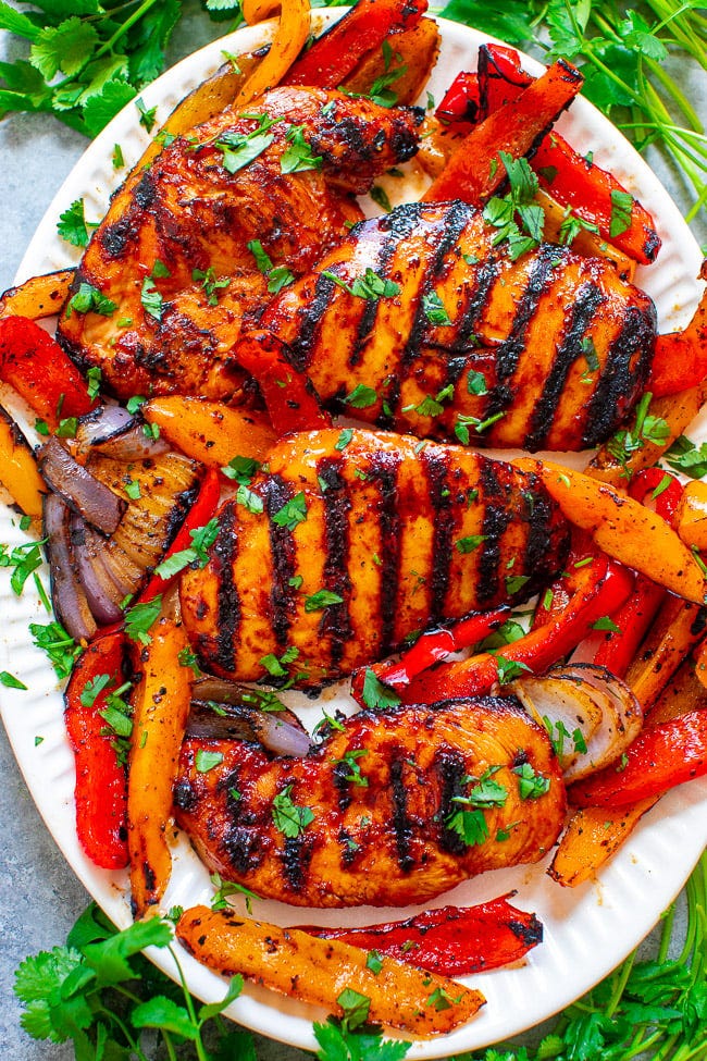Grilled spicy BBQ chicken and veggies on a white platter. Grilled spicy BBQ chicken and veggies on a white platter.