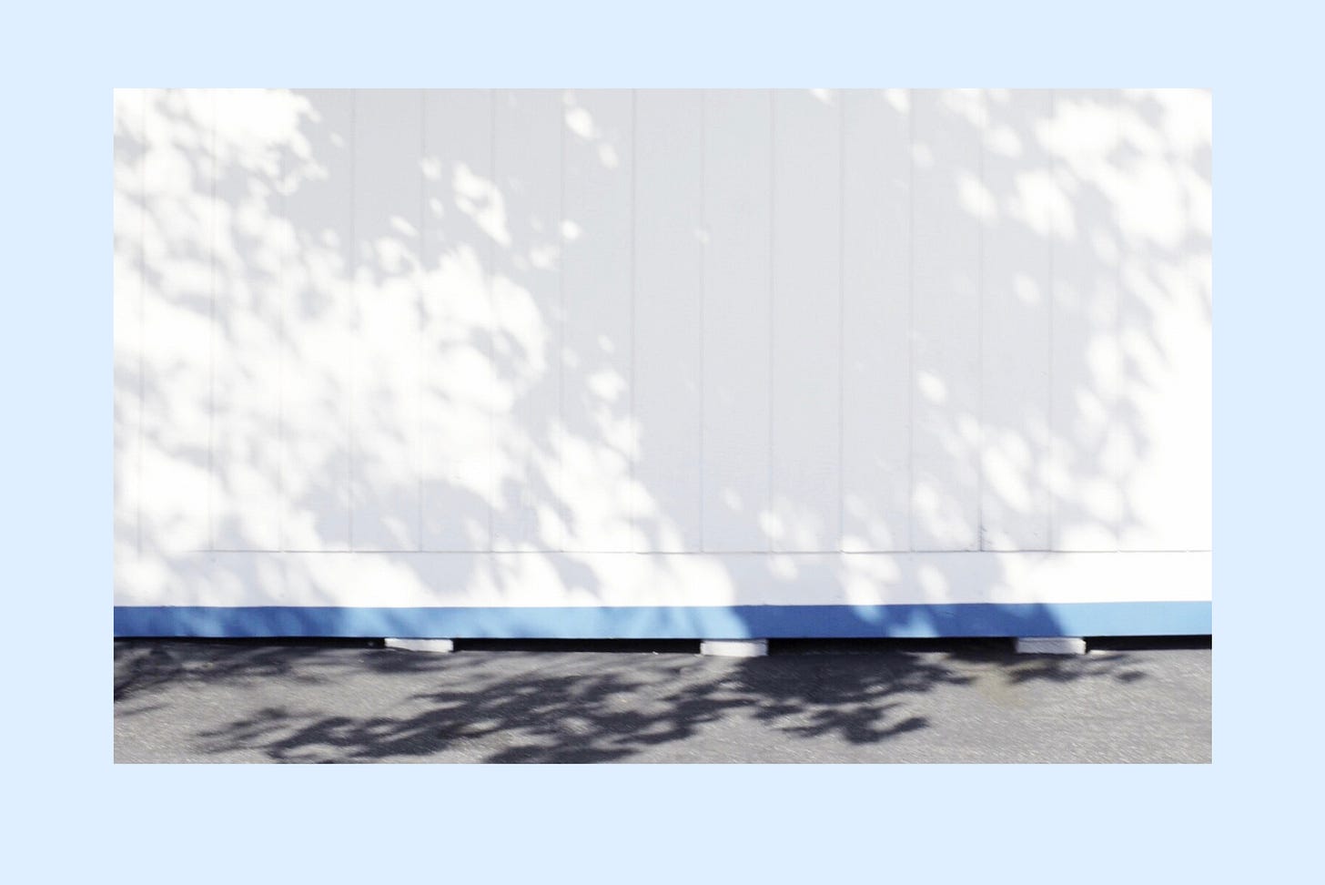 Late day shadows falling in stripes across a blue and white wall, no people in the frame Late day shadows falling in stripes across a blue and white wall, no people in the frame