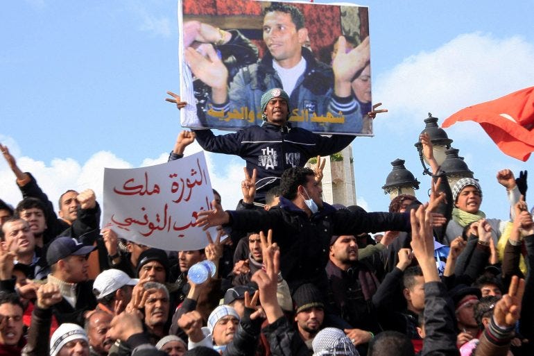 In a photo from January 2011, Tunisian protesters demonstrate beneath a poster of Mohamed Bouazizi, near the prime minister's office in Tunis [File:Salah Habibi/AP Photo]