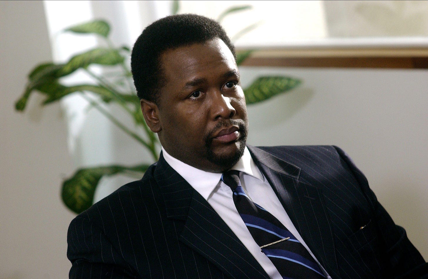 Wendell Pierce as Detective Bunk Moreland in The Wire, wearing a suit and tie and looking off-camera with a measured expression.