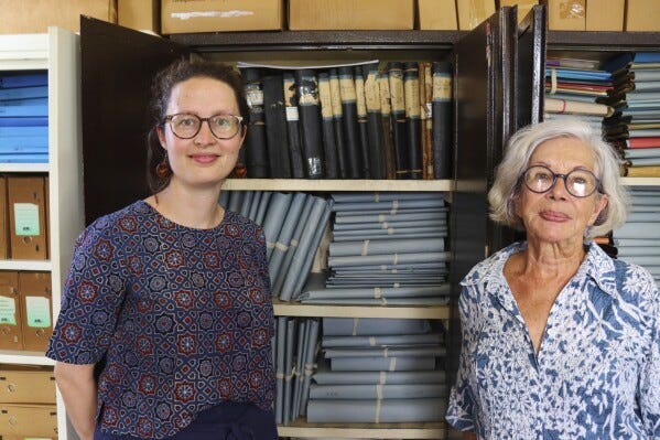 Rosa de Jong, left, and Lilly Duijm pose in front of the boxes of documents from the archive in Paramaribo, Suriname, Friday, May 2, 2025. (AP Photo/Oscar Keur)