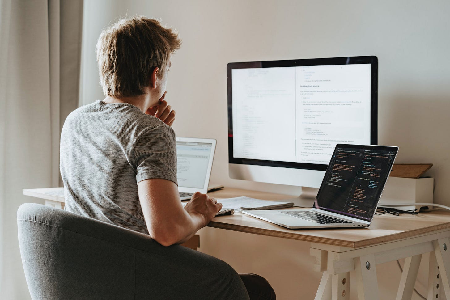 Man sitting at desk with 2 computer screens Man sitting at desk with 2 computer screens