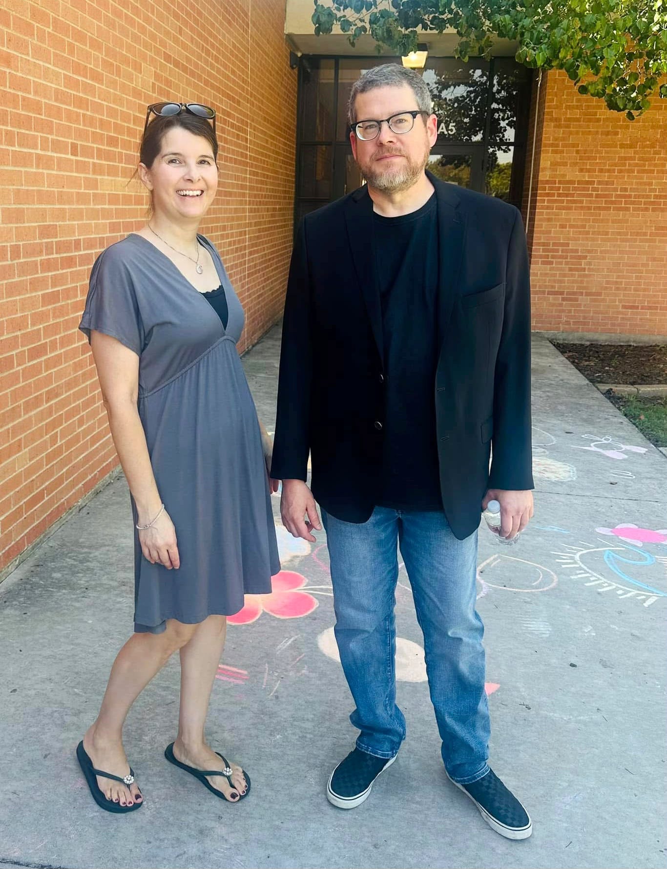 Alex Grecian and his wife standing in a school courtyard trying not to look like it's a hundred degrees out. Alex Grecian and his wife standing in a school courtyard trying not to look like it's a hundred degrees out.