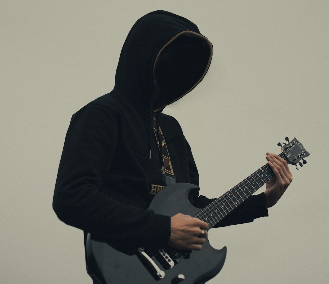 a man in a hooded jacket playing a guitar a man in a hooded jacket playing a guitar