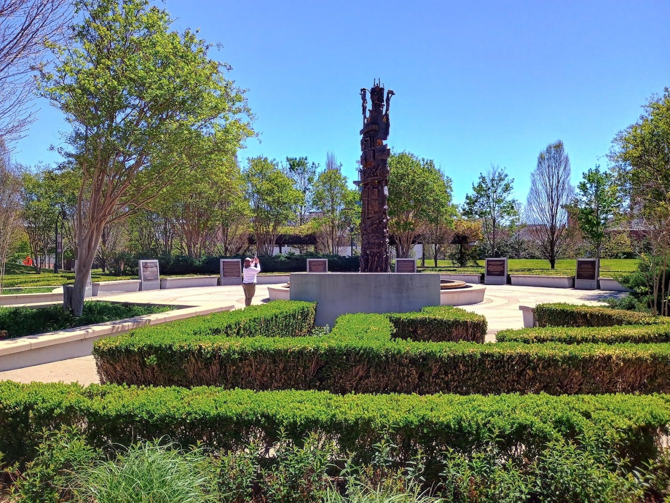 Park with circular area including info panels and large irregularly shaped sculpture at center