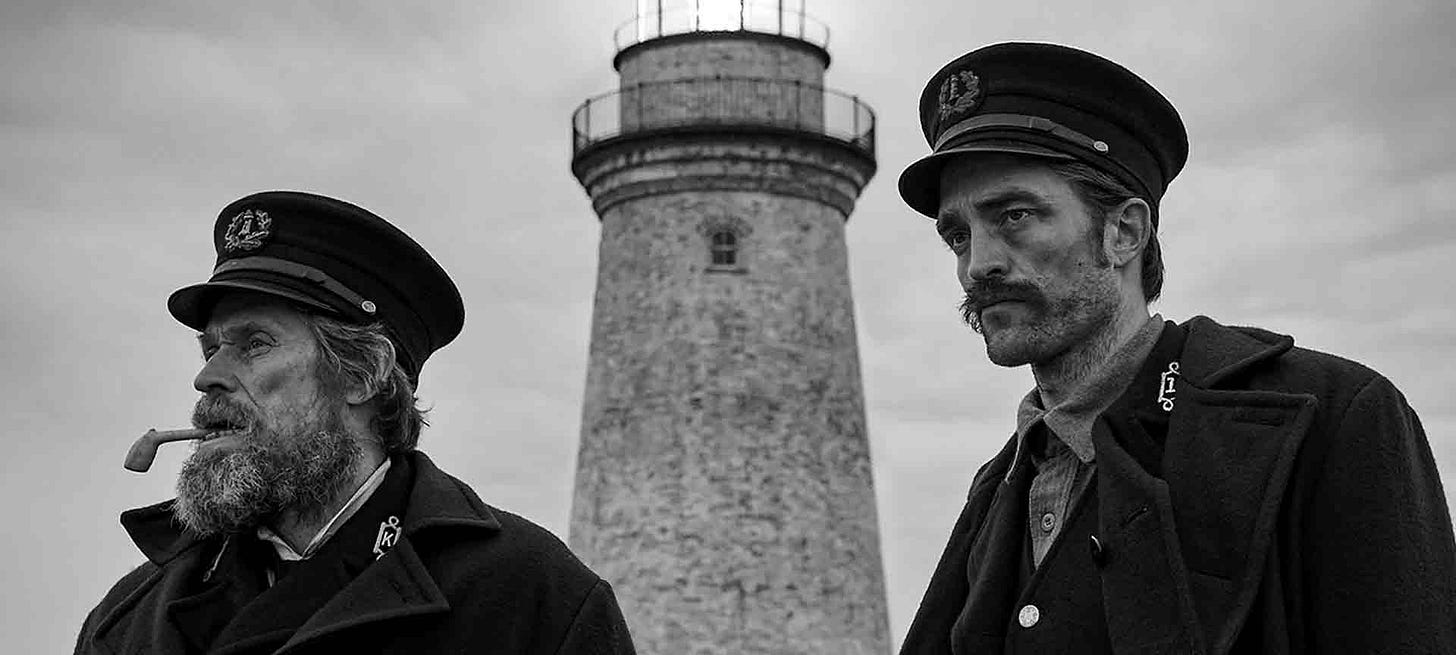 Wake and Howard in front of the isolated lighthouse in A24’s The Lighthouse, a psychological horror film set at sea.