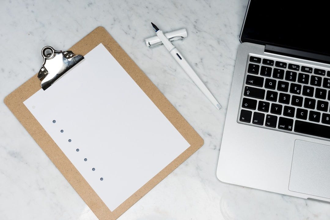 white printer paper beside silver laptop computer