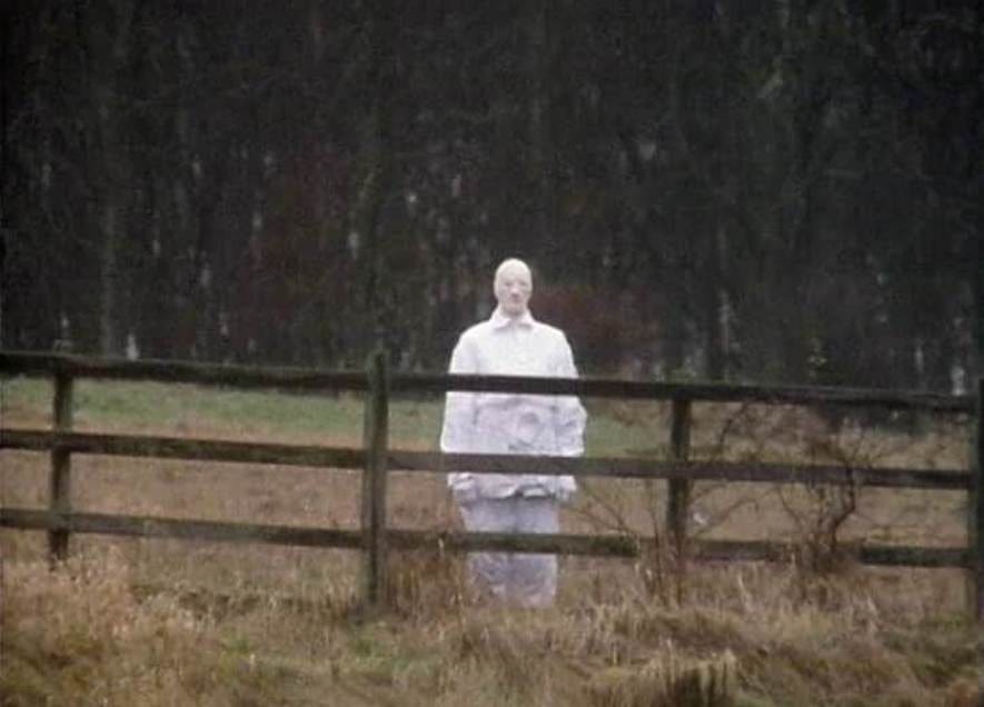 The Watcher: a silent figure in white, standing at a distance in an open field. Doctor Who, "Logopolis" (1981). The Watcher: a silent figure in white, standing at a distance in an open field. Doctor Who, "Logopolis" (1981).