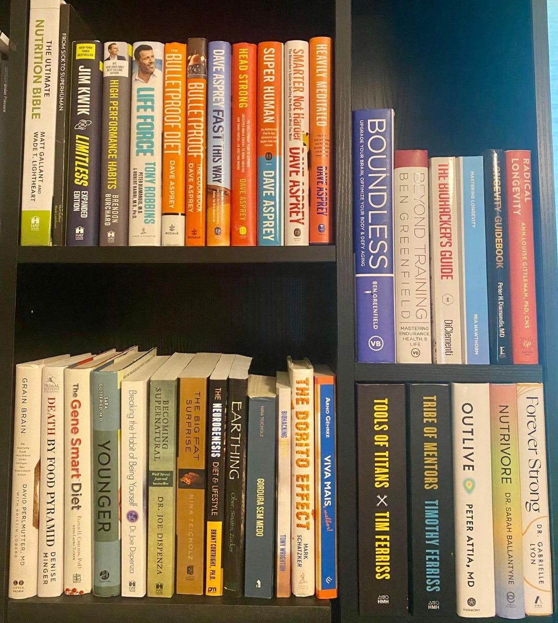 Estante cheia de livros sobre saúde e bem-estar, com títulos como 'The Bulletproof Diet', 'Superhuman', 'Tools of Titans' e 'The Biohacking Code', exibindo uma variedade de guias para performance e longevidade.