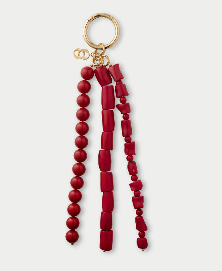 suede leather tote bag with gold buckle detail like the row bag featuring short borwn handles and gold and red trendy bag charm with polished gold hardware and branding