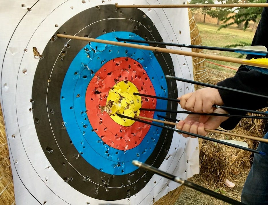 a group of people holding arrows in front of a target a group of people holding arrows in front of a target