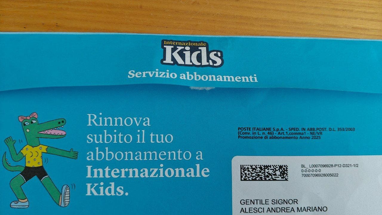 Busta blu da parte di "Internazionale Kids Servizio abbonamenti" che pubblicizza il rinnovo. In evidenza, il logo della rivista e una grande illustrazione di un coccodrillo verde in tenuta sportiva che saluta. Il testo principale recita: "Rinnova subito il tuo abbonamento a Internazionale Kids." In basso a destra sono visibili i dati postali (Poste Italiane), un codice a barre e l'intestazione formale "GENTILE SIGNOR ALESCI ANDREA MARIANO".