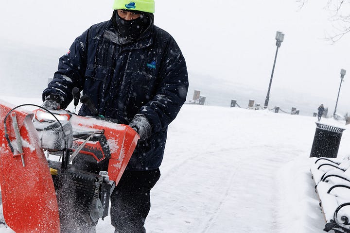Snowblower operator clearing the HarborWalk during a whiteout snow squall in Boston Seaport.