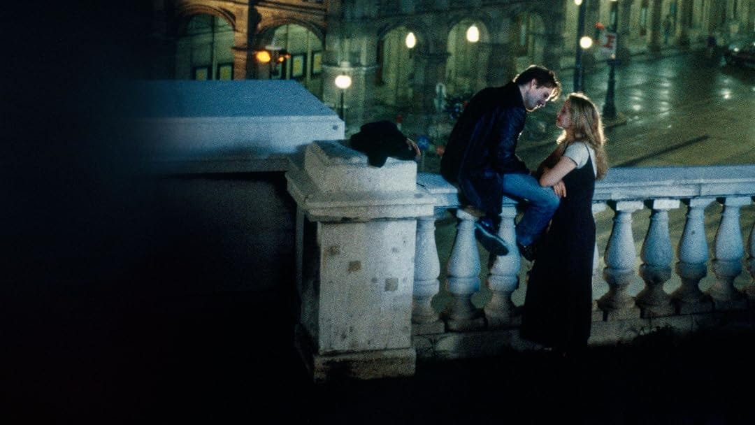 imagem do filme "antes do amanhecer", um casal branco em uma cidade histórica europeia à noite. eles se olham encantados um com o outro.