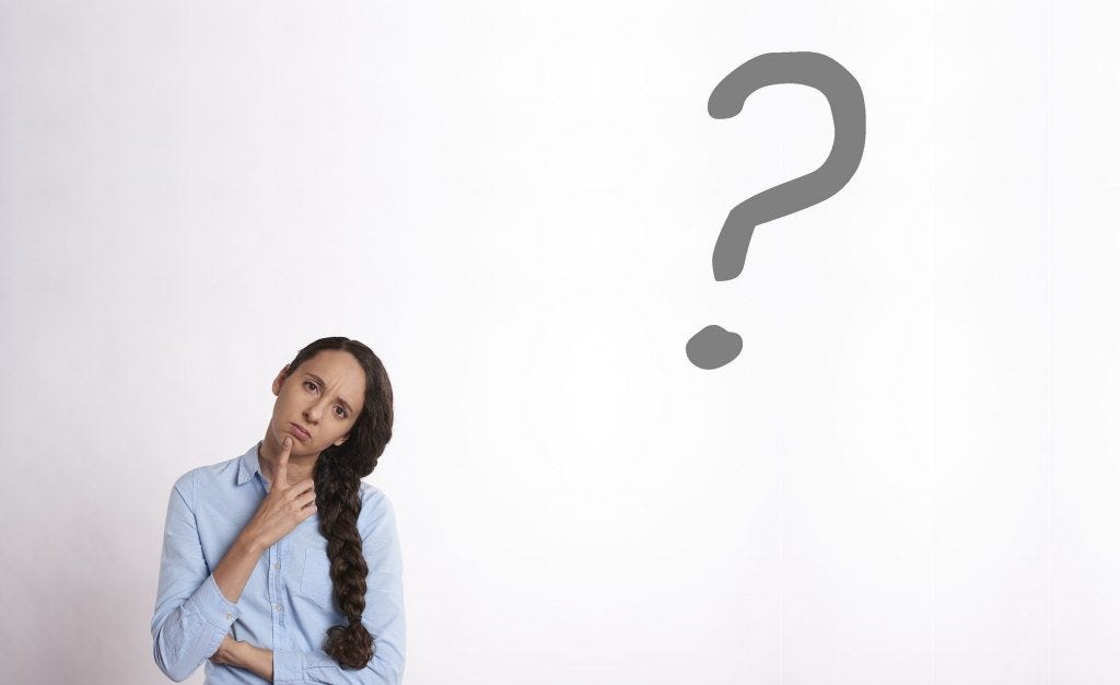 Woman with long brown hair and blue blouse looking thoughtful with a large question mark near her head asking Should I be writing this scene? Woman with long brown hair and blue blouse looking thoughtful with a large question mark near her head asking Should I be writing this scene?