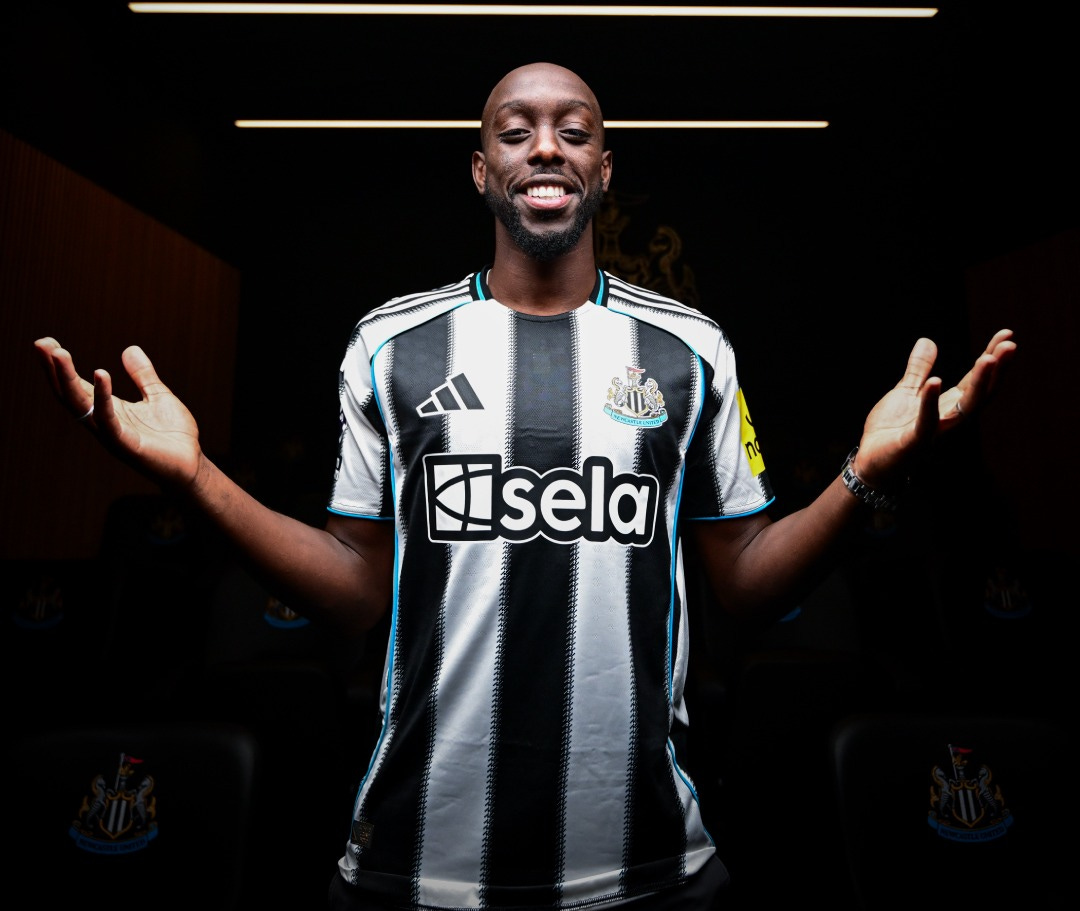 Yoane Wissa poses in a Newcastle United shirt with his arms to his side.