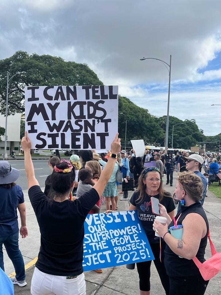 Protest signs that say "I can tell my kids I wasn't silent" and "ban billionaires not books"