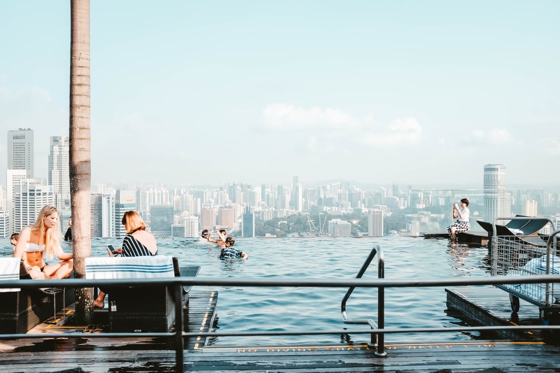 People Beside Pool Near Buildings People Beside Pool Near Buildings