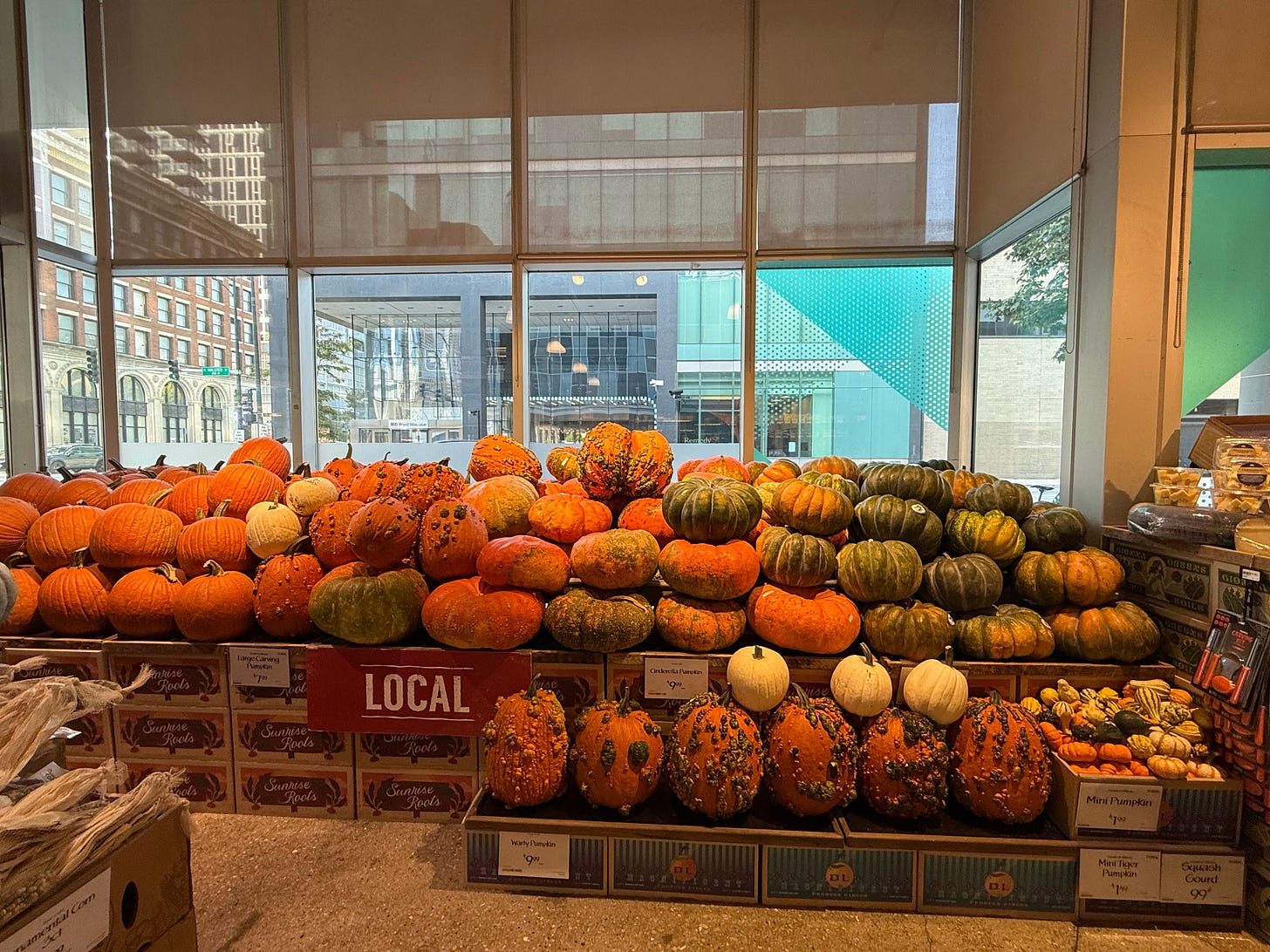 Stacks of local pumpkins and winter squash inside a city market, sunlight filtering through tall windows. Stacks of local pumpkins and winter squash inside a city market, sunlight filtering through tall windows.