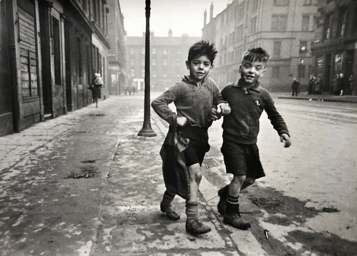 Two boys walking arm in arm down a street Two boys walking arm in arm down a street